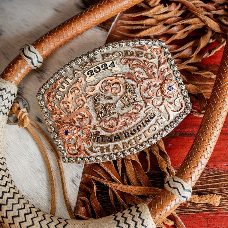 A custom trophy belt buckle featuring a silver plate finish for 2024 team roping champion